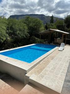 a large blue swimming pool next to a house at EL PEDREGAL Casa en Cafayate in Cafayate