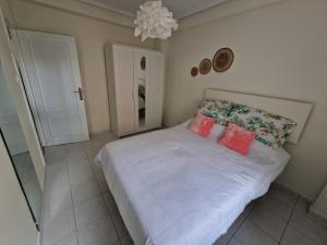 ein Schlafzimmer mit einem weißen Bett mit Kissen und einem Kronleuchter in der Unterkunft Piso Cesar de la Campa in Santander