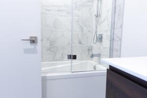 biała łazienka z wanną i prysznicem w obiekcie Amazing Condo with Spectacular Views for 8ppl w mieście Baie-Saint-Paul