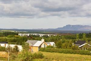 a house in a field with mountains in the background at Hótel Heiðmörk in Reykjavík