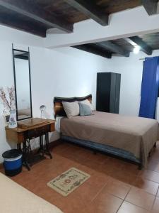 a bedroom with a bed and a desk and a mirror at Hotel Posada Don Papagon in Antigua Guatemala