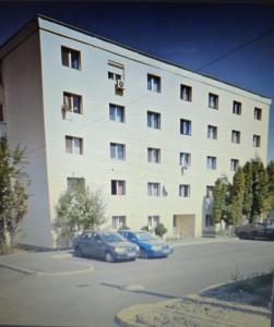 een groot wit gebouw met auto's geparkeerd op een parkeerplaats bij Vigaro Vgr in Braşov