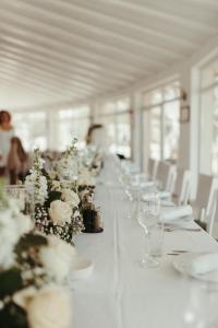 una larga mesa blanca con copas de vino y flores en Garni hotel Oblačinsko jezero, en Oblačina