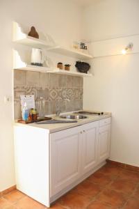 a kitchen with white cabinets and a sink at Auberge Kalopetri in Kamiros