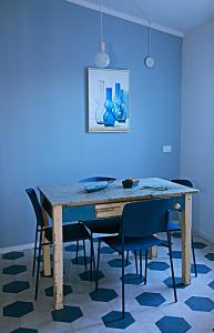 a dining room table with chairs and a blue wall at La Grigua blu in Riomaggiore