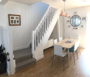 a dining room with a table and a staircase at Downtown Cottage Conwy in Conwy