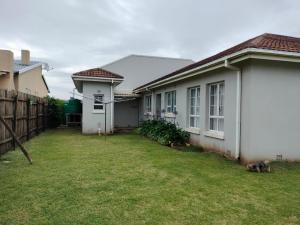 a backyard of a house with a dog laying in the yard at Adros in Kiddʼs Beach