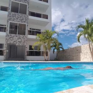 a man laying in a swimming pool next to a building at Tropical Beach Bayahibe in Bayahibe