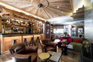 - un bar avec un canapé et des chaises dans la chambre dans l'établissement Hôtel La Bergerie, à Morzine