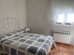 Un dormitorio con una cama con una manta azul y blanca. en Casa Azañas, en Casavieja 1 foto más