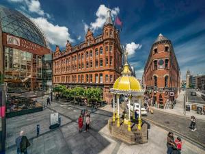 een groep mensen die in een stad wandelen met een gebouw bij Pass the Keys City Centre Queens Uni Eateries and Bars Abound in Belfast