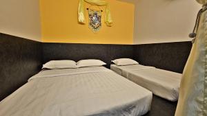 two twin beds in a room with yellow walls at Hogwart's Guesthouse in Semporna