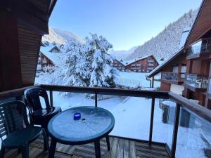 uma varanda com uma mesa e cadeiras e árvores cobertas de neve em Studio pieds des pistes plein soleil em Les Contamines-Montjoie