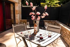 a table with two chairs and a bottle of wine and flowers at Gites spa de charme L ETOILE SPA in Beynac-et-Cazenac