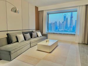 a living room with a couch and a large window at Shanghai Shining River Apartment -Near the Bund in Shanghai