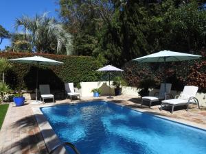 a swimming pool with two umbrellas and chairs at Beautiful 2-Bed Villa in Quinta do Lago with Pool in Quinta do Lago