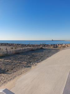 uma praia arenosa com o oceano ao fundo em T2 Montpellier plein sud clim wifi terrasse de 16m2 em Montpellier