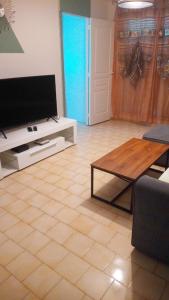 uma sala de estar com uma televisão e uma mesa de centro em T2 Montpellier plein sud clim wifi terrasse de 16m2 em Montpellier
