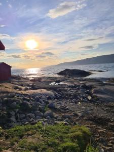 a sunset on a rocky beach near the ocean at Private Mountain Apartment in Narvik