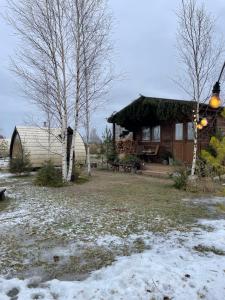 una cabaña de madera con nieve en el suelo frente a ella en Ambercoast en Jūrmala