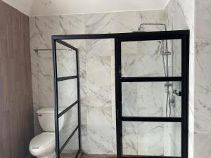 a bathroom with a toilet and a glass shower door at Casa Júpiter in Villahermosa