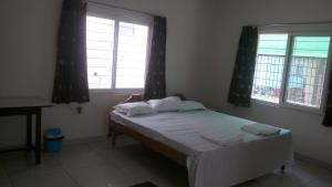a bed in a room with two windows at WeKare Archid Royal Service Apartment in Bhubaneshwar