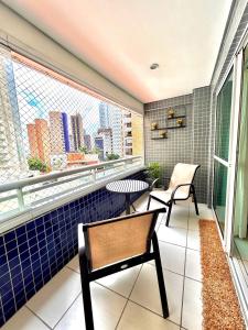 uma varanda com 2 cadeiras, uma mesa e uma janela em DN Apartamento no beach class ,VISTA MAR ,Fortaleza em Fortaleza