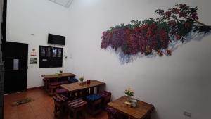 una habitación con mesas, sillas y flores en la pared en Hotel Posada Don Papagon en Antigua Guatemala