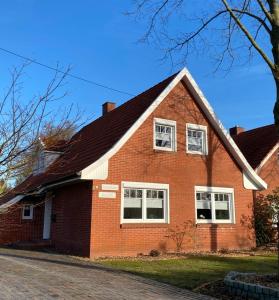 a red brick house with white windows on a street at Ferienhaus Auszeit in Westoverledingen