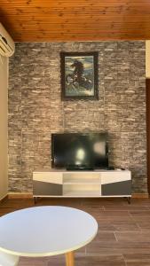 ein Wohnzimmer mit einem Flachbild-TV an einer Backsteinwand in der Unterkunft July Seaview Apartments in Sarandë