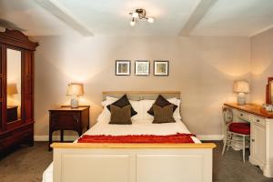 ein Schlafzimmer mit einem Bett und einem Schreibtisch mit zwei Lampen in der Unterkunft Wheatacre White Lion in Burgh Saint Peter