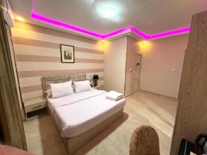 1 dormitorio con 1 cama blanca con iluminación rosa en Pyramids Nun INN en El Cairo
