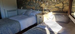 1 dormitorio con 2 camas y pared de piedra en PALLERO BAIXO, en Las Colladas