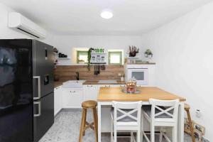 a kitchen with a wooden table and a black refrigerator at Villa Agora - Betina in Betina