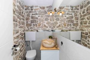 a bathroom with a toilet and a stone wall at Villa Agora - Betina in Betina