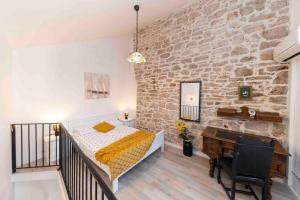 1 dormitorio con cama, escritorio y pared de piedra en Villa Agora - Betina en Betina