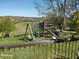 a playground in a park with a wooden fence at La maison du colibri 