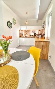 a kitchen with a white table and yellow chairs at Apartament Yellow Mielno in Mielno