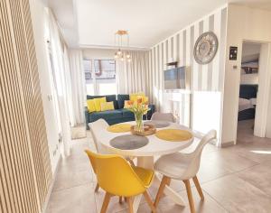 - un salon avec une table blanche et des chaises jaunes dans l'établissement Apartament Yellow Mielno, à Mielno