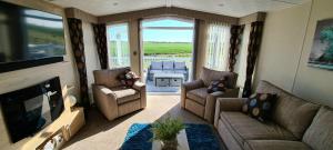 a living room with a couch and chairs and a television at Golden Anchor Caravan Park, Europa Sequoia Private Static Caravan Hire on Wildflower Meadow in Chapel Saint Leonards