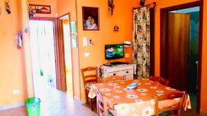 ein Esszimmer mit Tisch und Fernseher in der Unterkunft Villetta VIRGINIA in Torre Pali 