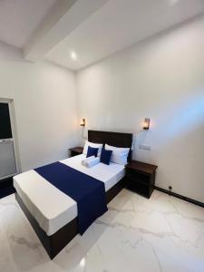 a bedroom with a large bed with blue and white sheets at Devon Surf . Inn - Hiriketiya in Dickwella