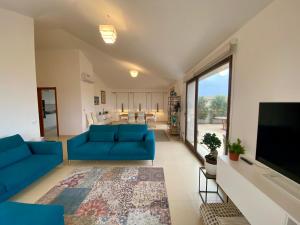 a living room with blue couches and a flat screen tv at Penthouse Le Isole - Luxury rooftop retreat in Marsala