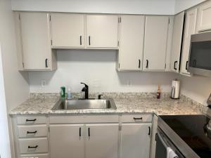 een keuken met witte kasten en een wastafel bij Peaceful Park 2 Bedroom Remodeled Family Suite in Granite City
