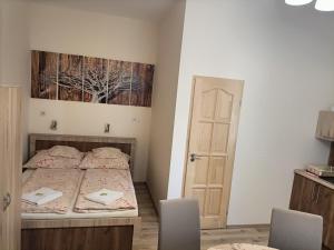 ein Schlafzimmer mit einem Bett mit zwei Stühlen und einer Tür in der Unterkunft Elizabeth Apartman in Makó