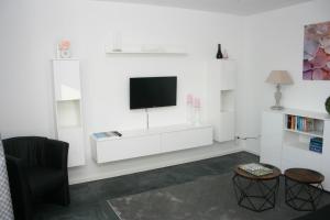 - un salon avec une télévision sur un mur blanc dans l'établissement Ferienwohnung Die Idyllische mit Sauna, à Clèves