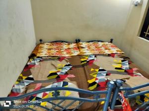 a bed with a colorful comforter on top of it at SS GUEST HOUSE & PG in Kumbakonam
