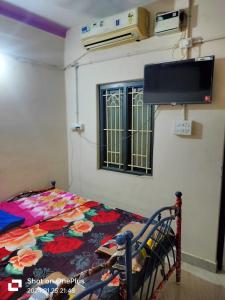 a bedroom with a bed and a tv on the wall at SS GUEST HOUSE & PG in Kumbakonam