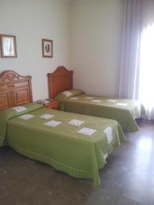 a room with three beds with green sheets at Hotel Luz de Guadiana in Ayamonte