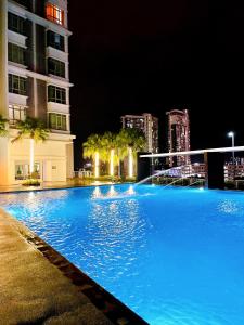 a large blue swimming pool at night with buildings at Cozy Stay at Shaftsbury Residences by SNS HOMES in Cyberjaya